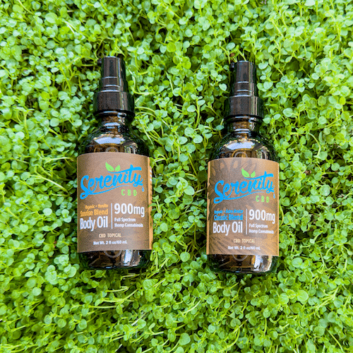 Serenity CBD Body Oil Combo with two 900mg bottles placed on fresh green grass—promoting natural skin nourishment, relaxation, and soothing wellness