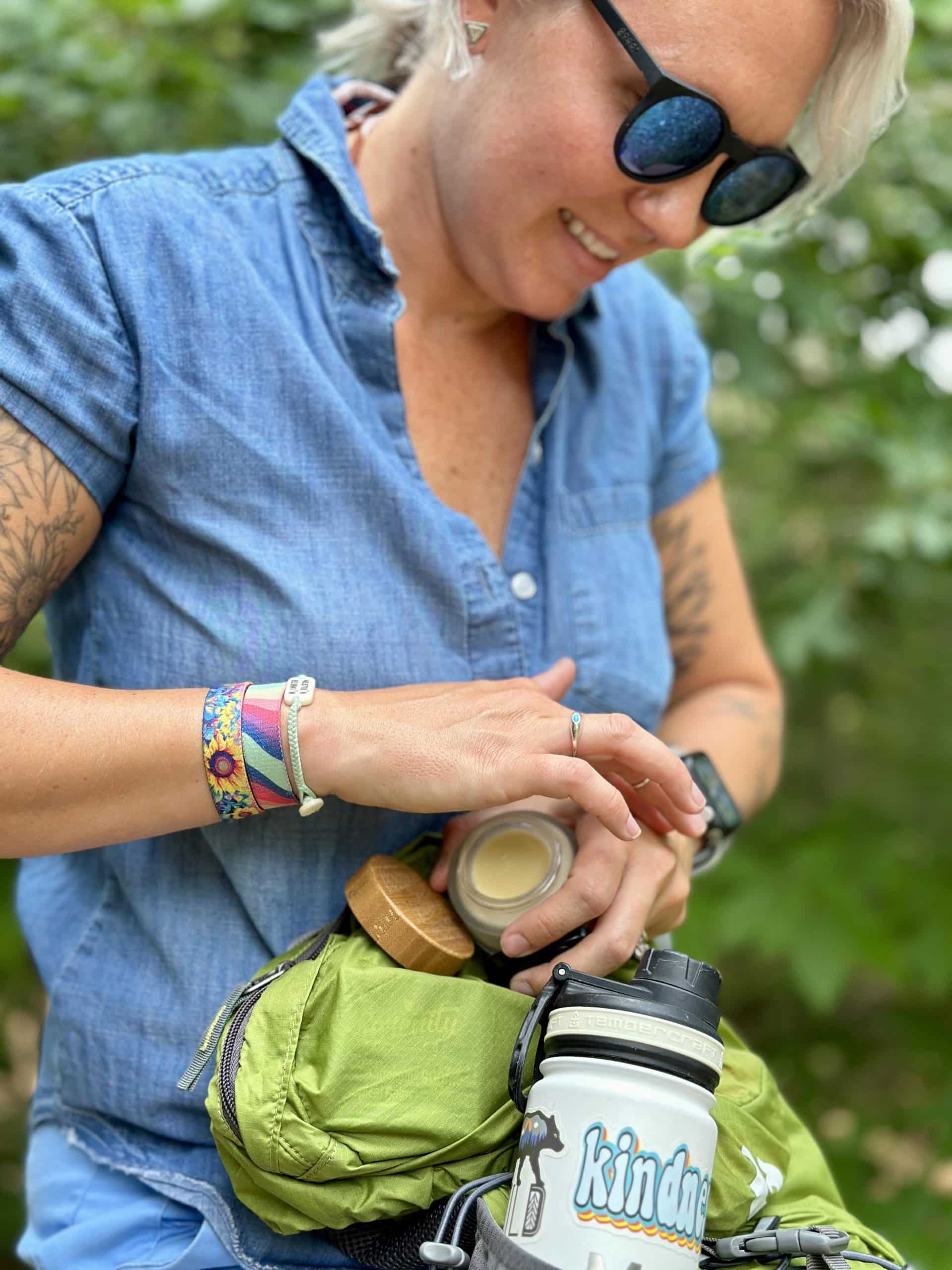 Women outdoors putting Serenity CBD Topical Balm into a backpack—showcasing convenient, on-the-go relief for active lifestyles