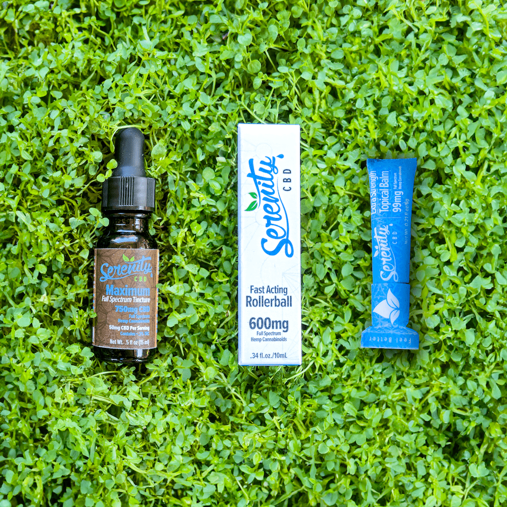 Serenity CBD tincture, fast-acting rollerball, and topical balm arranged on fresh green grass—symbolizing natural relief, balance, and plant-powered self-care