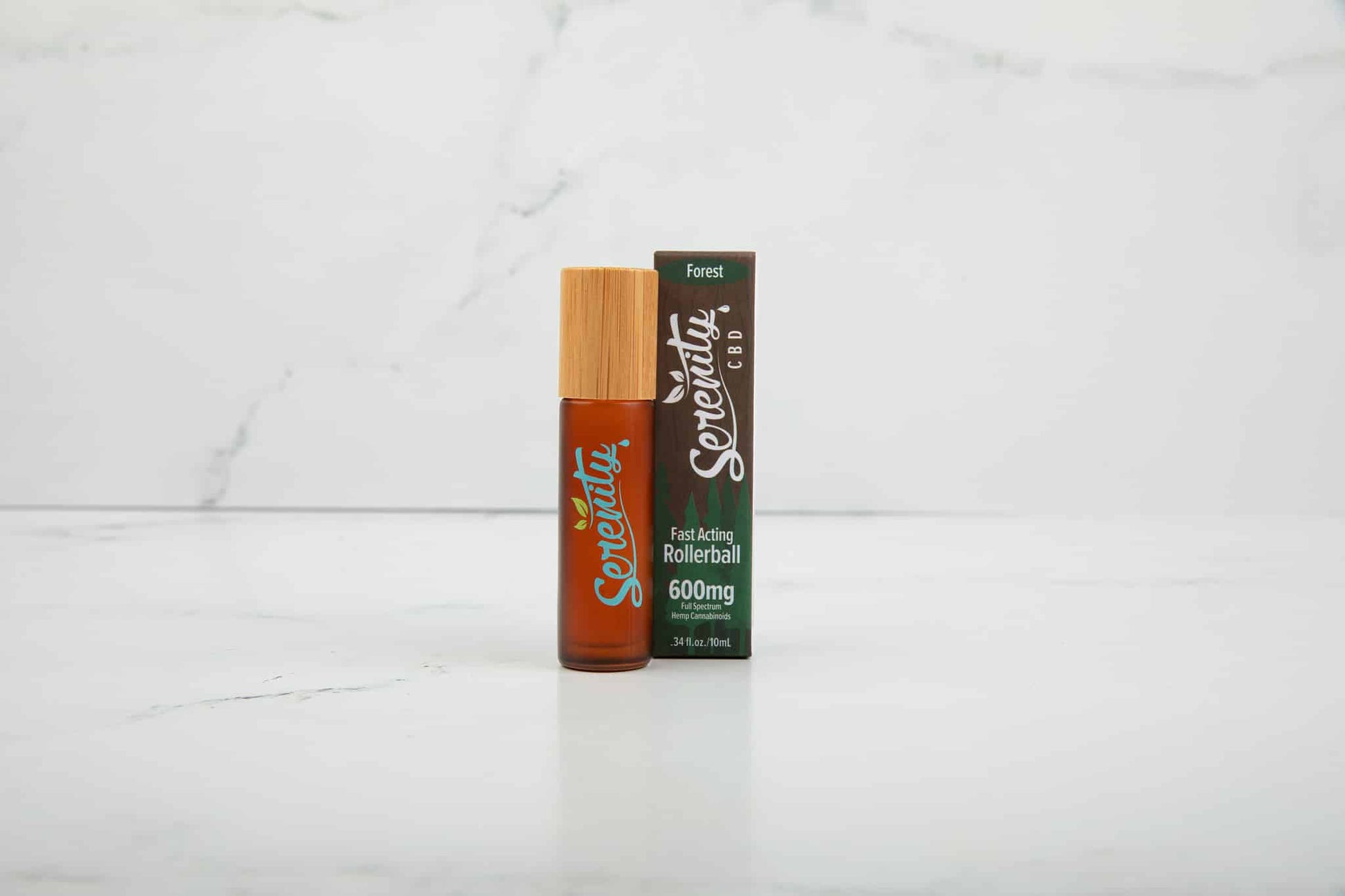 Serenity CBD Forest Blend Roller with packaging on a clean marble surface—designed for fast-acting relief and grounding, nature-inspired wellness