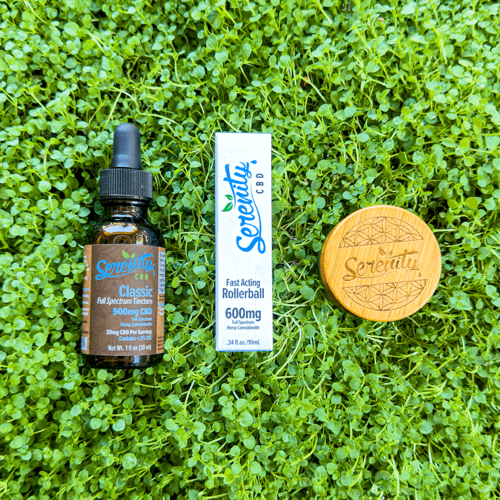 Serenity CBD Classic Full Spectrum Tincture, Fast Acting 600mg Rollerball, and a bamboo-lid jar arranged on fresh green grass—symbolizing natural relief, balance, and plant-powered wellness