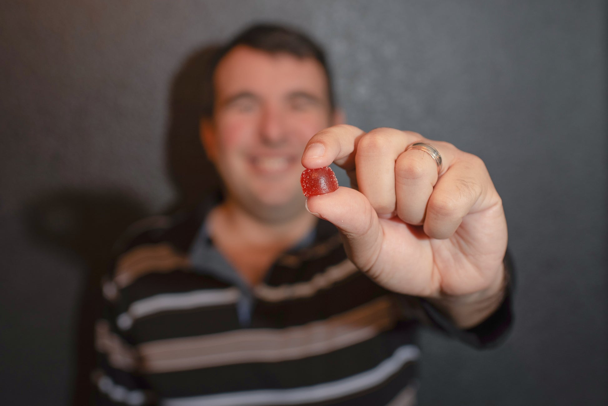 Smiling person holding a red Serenity CBD ‘Relief’ gummy—highlighting approachable, everyday wellness and joy through plant-powered balance