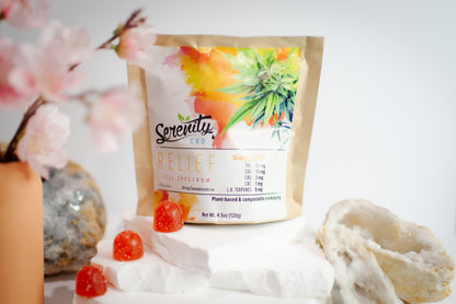 Serenity CBD ‘Relief’ full spectrum gummies pouch displayed with cherry blossoms, crystals, and bright orange gummies—evoking natural harmony, plant-based relief, and mindful wellness