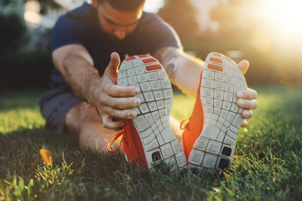 An image of a man stretching before a run to help combat the effects of adenosine in the body early in the morning.