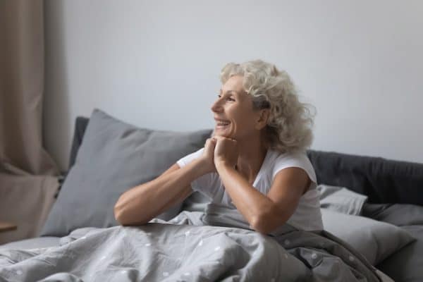 Image of a mature woman excited to wake up feeling refreshed after using a cbd sleep tincture.