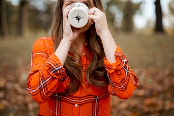 Close-up of a woman sipping coffee, symbolizing the peaceful and grounded feeling that comes from embracing Ayurvedic practices during the fall season.